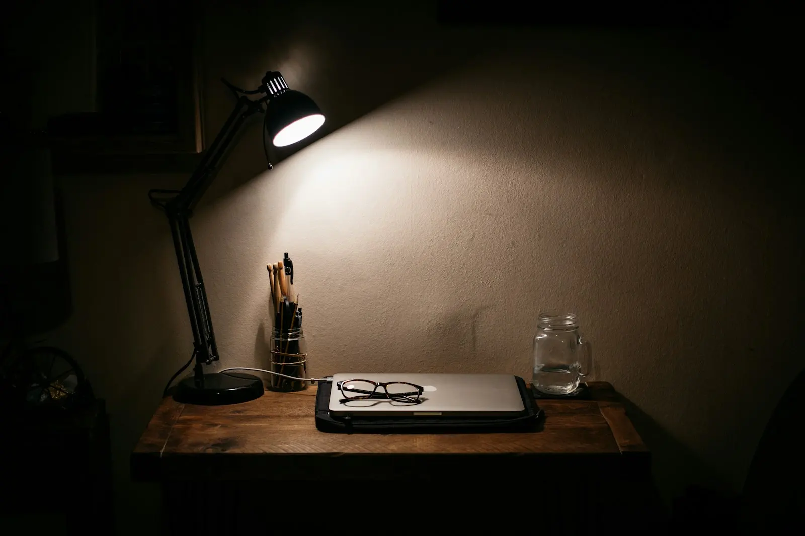暗い部屋で、机のランプだけが灯っている様子